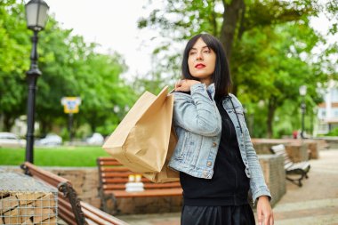 Elinde bir kaç tane kağıt torba ve satın alınmış şeyler olan bir kadın parkta yürüyordu, alışveriş yaptıktan sonra da bir kız. Kara Cuma