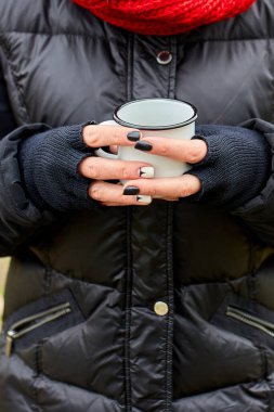 Kırmızı şapkalı ve eşarplı kadın, metal bardaktan çay içiyor, seyahat konsepti, sonbahar manzarası.
