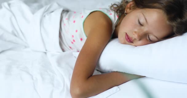 小さな女の子は家で午後に大きく居心地の良いベッドの白いリネンで寝て 家族のライフスタイル 快適な枕 ベッド — ストック動画