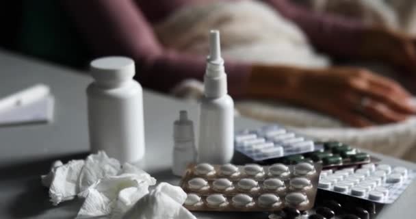 Mujer joven enferma midiendo la temperatura en casa en las pastillas y tabletas en el fondo — Vídeos de Stock