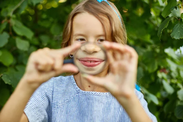 Mała Dziewczynka Bawiąca Się Szkłem Powiększającym Ogródku Robi Miny Koncepcja — Zdjęcie stockowe
