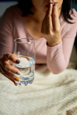 Hasta kadın eline ilaç alıp içti. Evde dinlenirken su içti. Hasta kadın evinde kanepede otururken hap aldı.