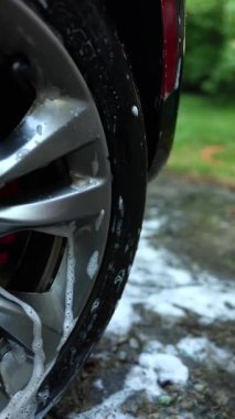 Güneşli bir öğleden sonra, arka bahçede sabun ve suyla araba tekerleğini temizlerken köpükler parlak çemberde görülebiliyor..