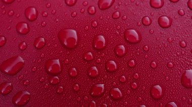 Canlı kırmızı bir yüzey berrak su damlacıklarıyla beneklenerek su ve renklerin etkileşimini vurgulayan ilginç bir doku oluşturulur. Bu sahne sadelikle zarafeti yakalar..