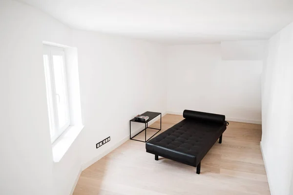 白色房间里的一个黑色现代日光浴沙发 — 图库照片