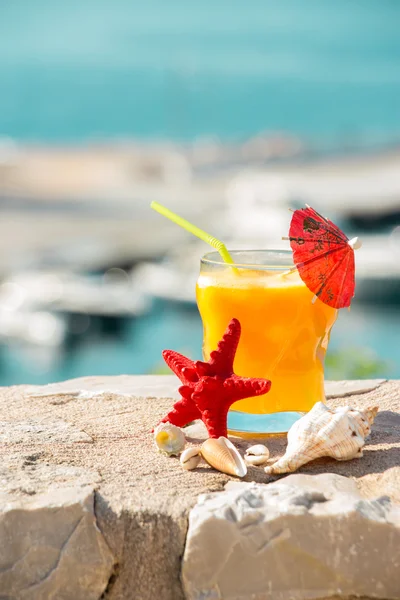 Sumo de laranja, mar e conchas . — Fotografia de Stock