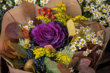 Çiçekçide güzel bir buket taze kesilmiş brassica oleracea ya da çiçek açan lahana ve diğer sonbahar çiçekleri, yapraklar ve böğürtlen. Yatay olarak. Gün ışığı. Yakın plan..