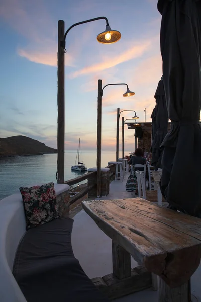 Egy varázslatos este egy kocsmában, gyönyörű kilátással a Kolona-öbölre az esti lámpások fényében - Kythnos sziget, Görögország, június 2021. — Stock Fotó