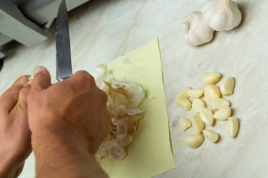 Erkek şef, sarımsağı mutfak bıçağıyla keser. 