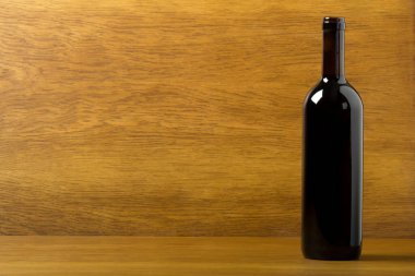 Ahşap arka planda kırmızı şarap şişesi.