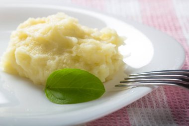 Patates püresi ve çatal ile beyaz tabakta fesleğen