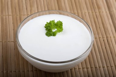 Ekşi krema kase bir yaprak maydanoz üzerinde ahşap masa örtüsü