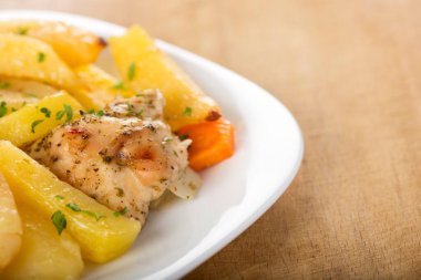 Patates ve beyaz plaka üzerinde otlar ile kavrulmuş tavuk