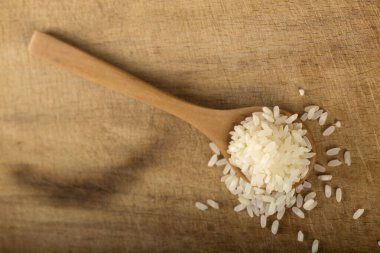 Tahta arka planda tahta kaşıkta biraz pirinç.