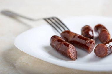 Sosis dilimleri ve beyaz tabakta bir çatal.