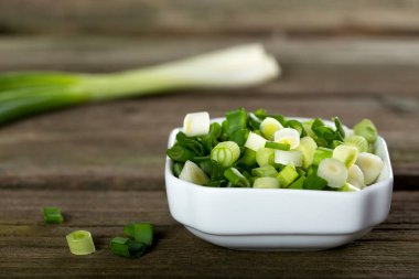 Ahşap arka plan üzerinde beyaz kase taze dilimlenmiş scallions