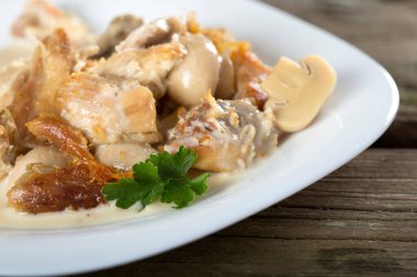 Kremalı soslu tavuk ve beyaz tabakta mantar.