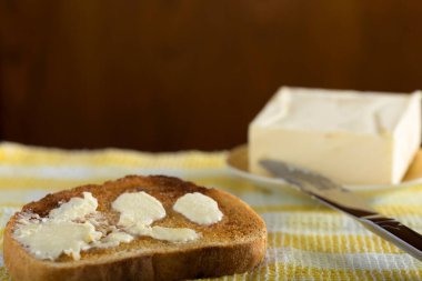 Bir tabak beyaz tereyağlı tost ve bıçak.
