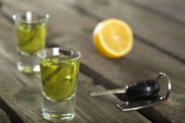 Arabanın anahtarlarını ahşap arka plan - içki sürücü kavramı üzerinde iki fondip bardakları ile