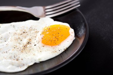 Siyah tabakta gümüş çatallı sahanda yumurtayı yakın.