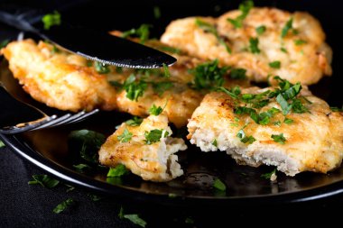 Siyah tabakta maydanozlu kızarmış tavuk şnitzel.