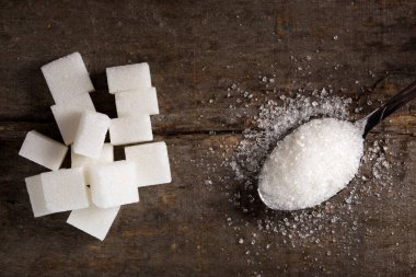 Beyaz ahşap masa üzerinde gümüş kaşık şeker