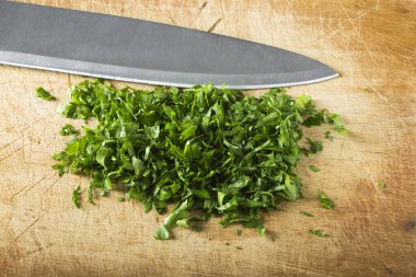 Ahşap kesme tahtası bıçakla üzerine kıyılmış maydanoz