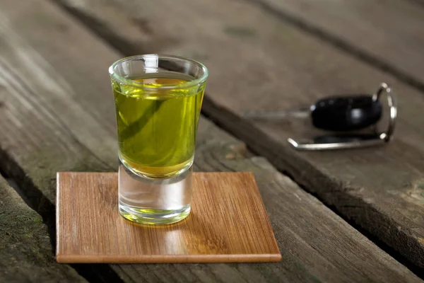 Arabanın anahtarlarını ahşap arka plan - içki sürücü kavramı üzerinde bir fondip bardakları ile