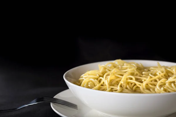 Plaka kopya alanı ile siyah arka plan üzerine haşlanmış İtalyan spagetti