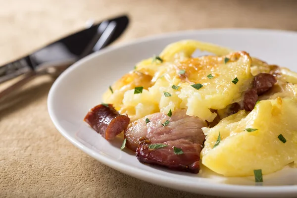 Peynir, pastırma ve sosis beyaz plaka üzerinde fırında patates