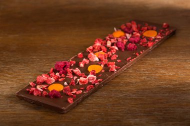 Ahşap arka plan üzerinde portakal, çilek ve ahududu sütlü çikolata