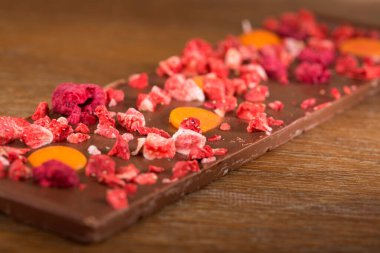 Ahşap arka plan üzerinde portakal, çilek ve ahududu sütlü çikolata