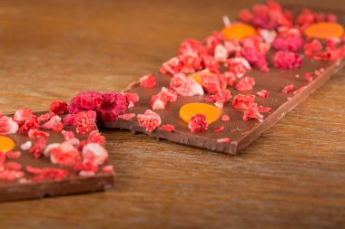 Ahşap arka plan üzerinde portakal, çilek ve ahududu sütlü çikolata