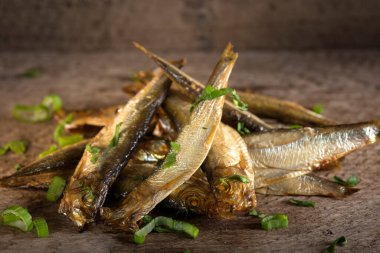 Kırsal ahşap masanın üzerinde bitkilerle tütsülenmiş balıklar.