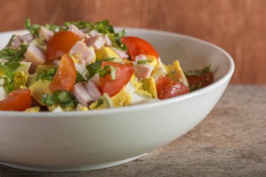 Yumurta ve jambon beyaz tabakta salatası bir ahşap arka plan üzerine yerleştirilen