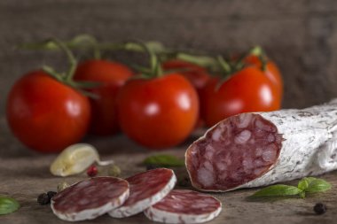 Baharatlar ve sebzeler üzerinde rustik ahşap arka plan ile İtalyan salamı