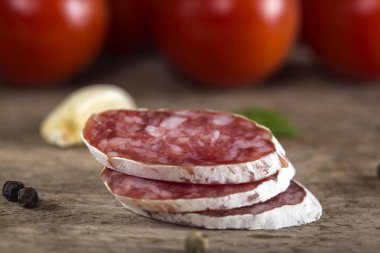 Rustik ahşap arka plan üzerinde İtalyan salam dilimleri baharat ve sebzeler ile yakından