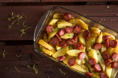 Tepsi sosis ve ahşap zemin üzerine baharat ile kızarmış patates ile
