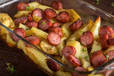 Tepsi sosis ve ahşap zemin üzerine baharat ile kızarmış patates ile