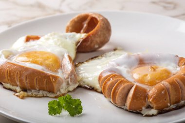 Kızarmış sosis ve beyaz tabakta yumurta.