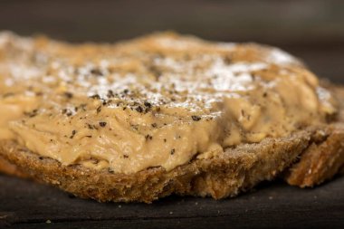 Ekmek dilimini, ahşap arka planda ev yapımı domuz ciğeri ezmesiyle kapat.