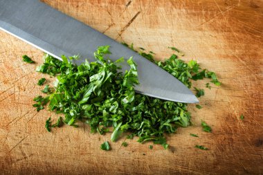 Kesme tahtasındaki bıçakla doğranmış maydanoz.