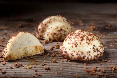 İki vanilyalı inci şeker, ikiye bölünmüş ve ahşap arka planda siyah çikolata rendelenmiş.