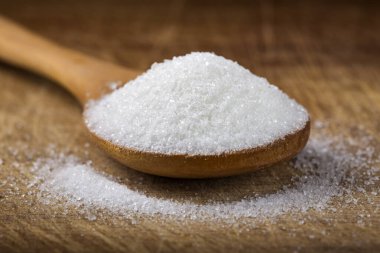 Tahta zemin üzerinde beyaz şekerle dolu bir bambu kaşığı kapat.