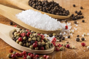 Ahşap zemin üzerinde deniz tuzu ve karabiber bulunan tahta kaşıklar. Sığ noktalı Macro.