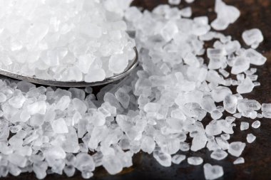 Paslanmaz çelik kaşıkla paslı arka planda deniz tuzunu kapat.