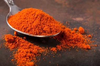 Paslı arka planda kırmızı biber tozu dolu kaşık