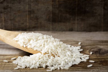 Ahşap arka planda pirinç dolu ahşap kaşık.