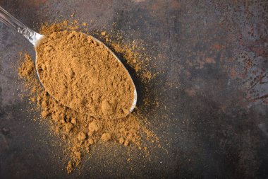 Paslı arkaplanda tarçın tozuyla doldurulmuş kaşık.