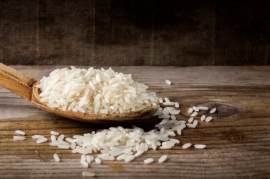 Ahşap arka planda pirinç dolu ahşap kaşık.